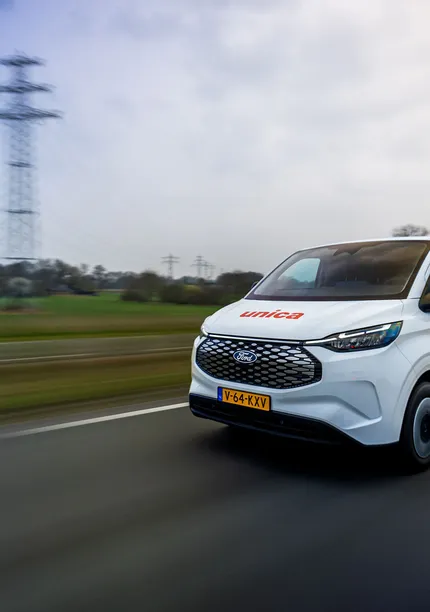 Unica bus rijdt over de snelweg door een landelijk landschap.