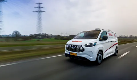 Unica bus rijdt over de snelweg door een landelijk landschap.