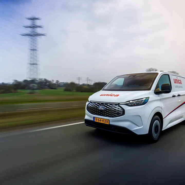 Unica bus rijdt over de snelweg door een landelijk landschap.