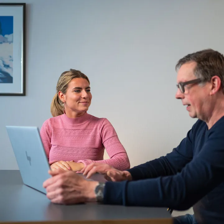 Unica-medewerker toont klant rapportage of besparingsplan in energieadviesgesprek.