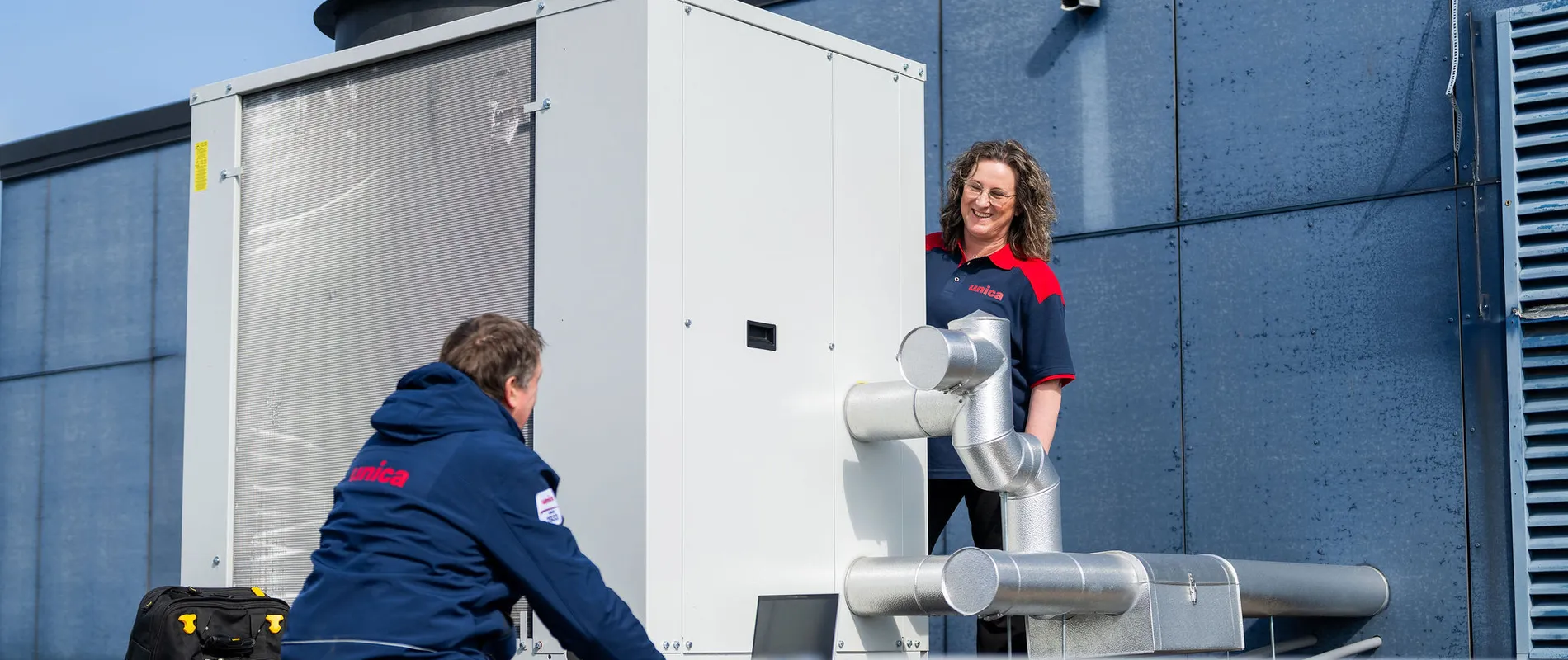 Twee technici van Unica bespreken werking en onderhoud van dakinstallatie bij zonne-energieopwekking.