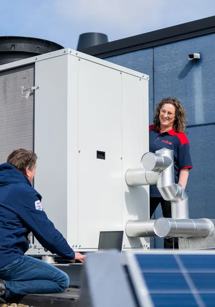 Twee technici van Unica bespreken werking en onderhoud van dakinstallatie bij zonne-energieopwekking.