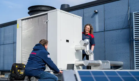 Twee technici van Unica bespreken werking en onderhoud van dakinstallatie bij zonne-energieopwekking.