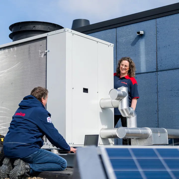 Twee technici van Unica bespreken werking en onderhoud van dakinstallatie bij zonne-energieopwekking.