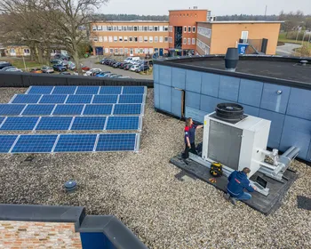 Monteurs inspecteren installatie naast PV-panelen als onderdeel van energieopwekking en wet- en regelgeving.