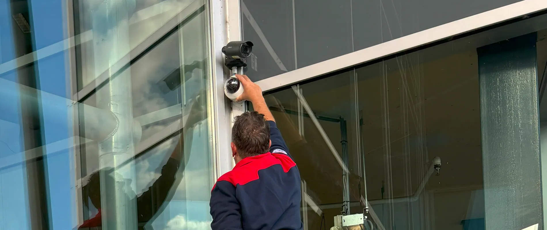 Man installeert camera aan wand