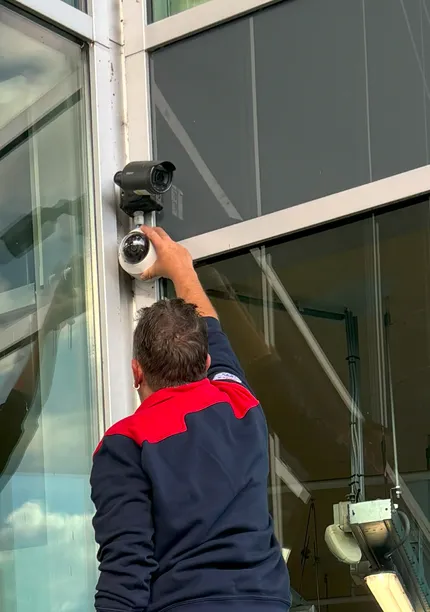 Man installeert camera aan wand