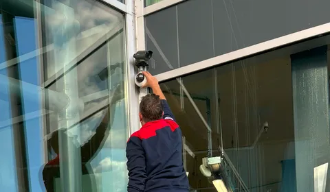 Man installeert camera aan wand