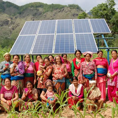 Nepalese vrouwen in Accham in kleurrijke kledij in een veld met op de achtergrond zonnepanelen