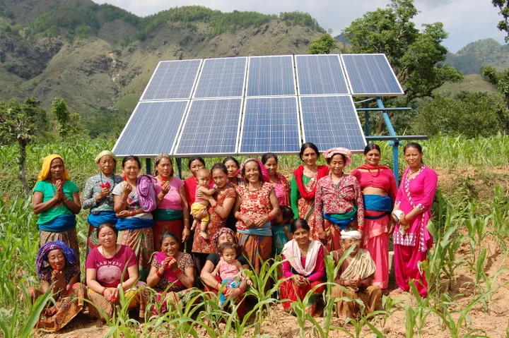 Nepalese vrouwen in Accham in kleurrijke kledij in een veld met op de achtergrond zonnepanelen