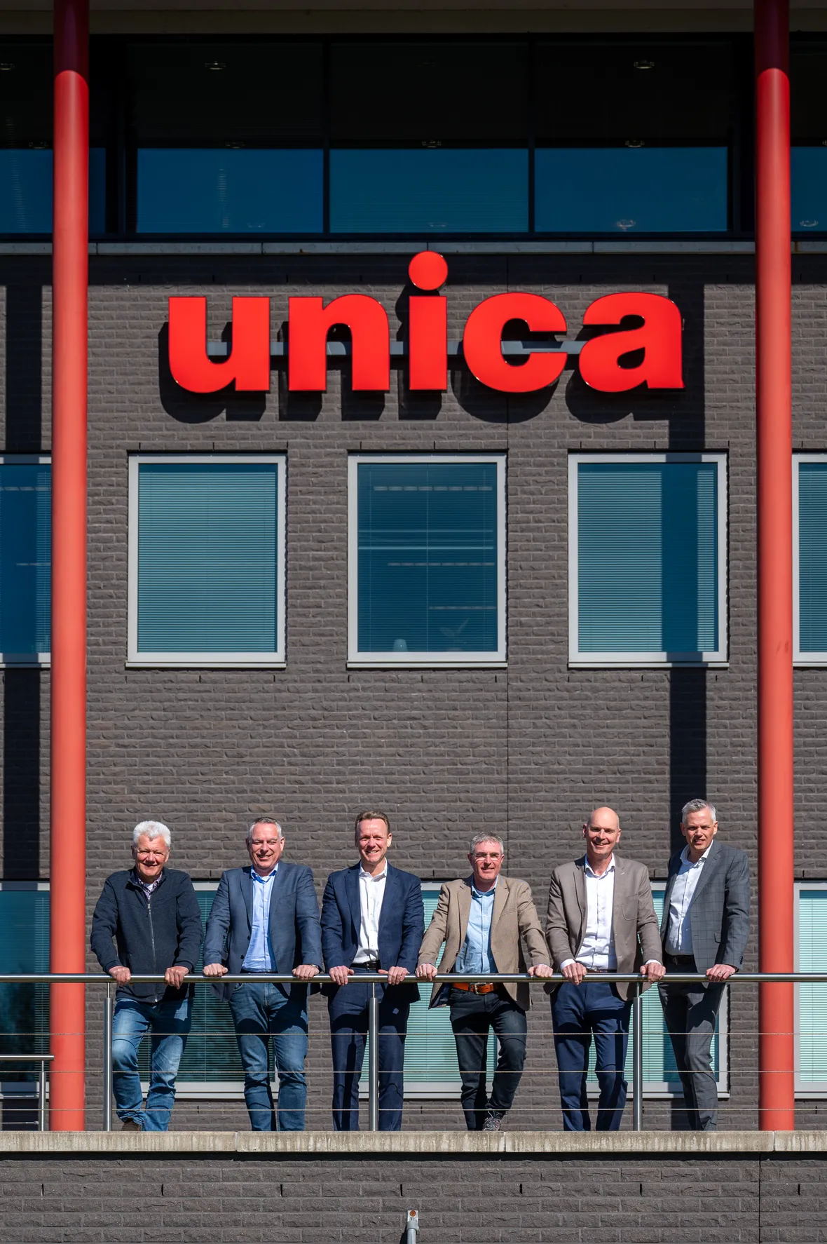 Het bestuur van MPL en van Unica staan lachend voor het Unica hoofdkantoor in Hoevelaken