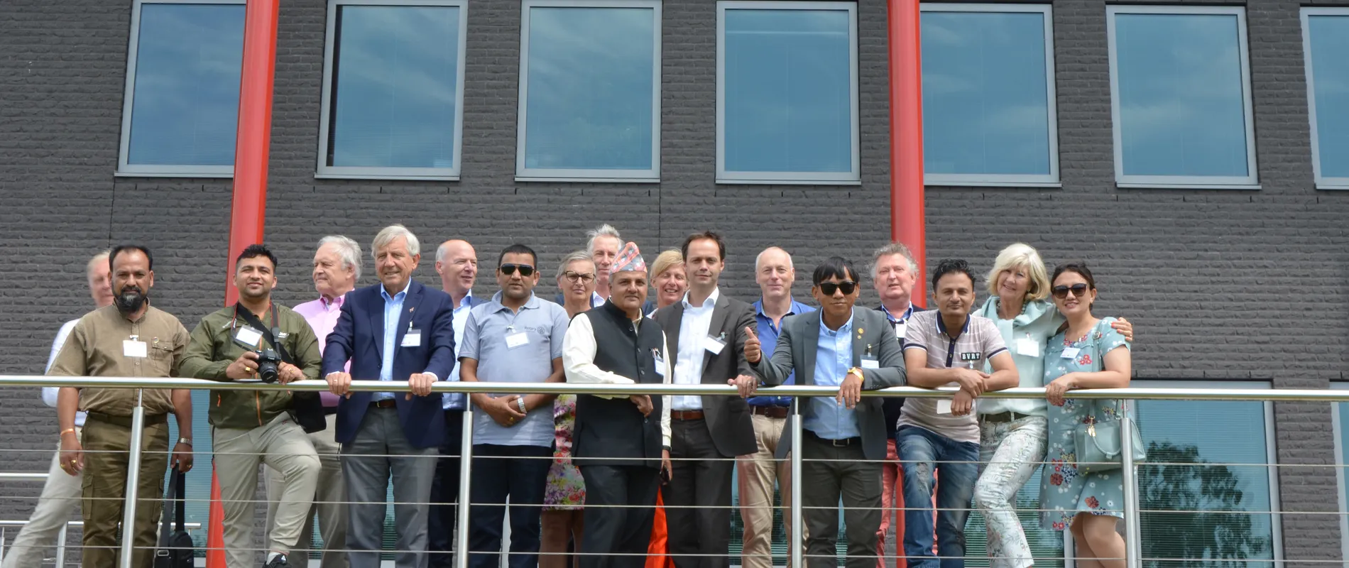 A group of people standing on a balcony in front of a building with the sign "unica."