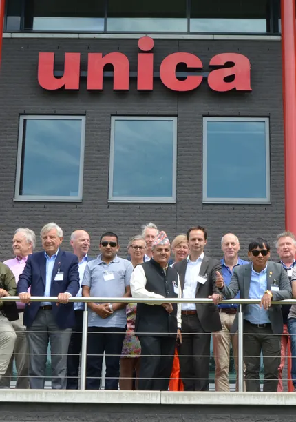 A group of people standing on a balcony in front of a building with the sign "unica."