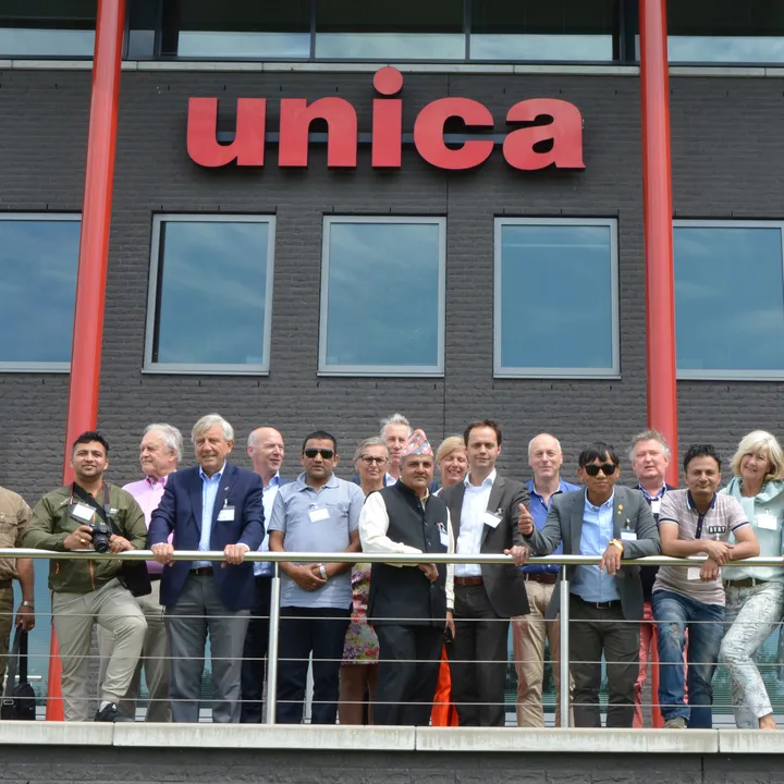 A group of people standing on a balcony in front of a building with the sign "unica."
