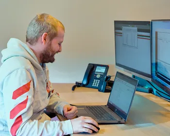 Medewerker van Unica werkt lachend aan zijn bureau