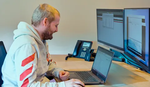 Medewerker van Unica werkt lachend aan zijn bureau