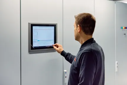 Medewerker van Unica checkt het gebouwautomatiseringssysteem via een wandpaneel