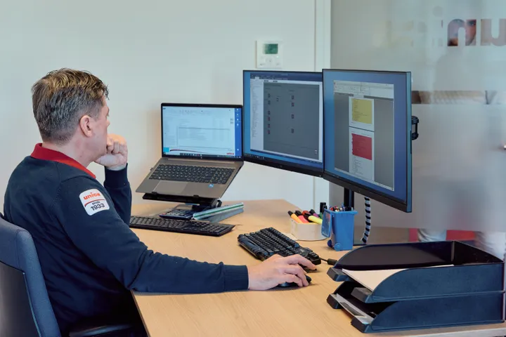 Medewerker van Unica kijkt geconcentreerd naar beeldscherm om systemen te monitoren