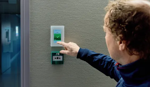 Medewerker van Unica bedient een touchpanel aan een technische installatie en checkt de status