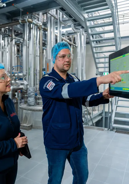 Unica-engineers bespreken een digitaal besturingssysteem via een groot HMI-touchscreen voor procesbewaking.