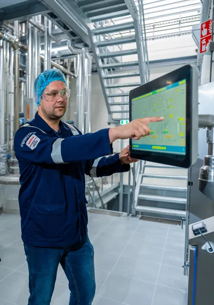 Unica-engineers bespreken een digitaal besturingssysteem via een groot HMI-touchscreen voor procesbewaking.
