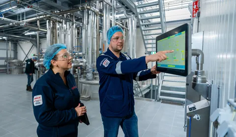 Unica-engineers bespreken een digitaal besturingssysteem via een groot HMI-touchscreen voor procesbewaking.