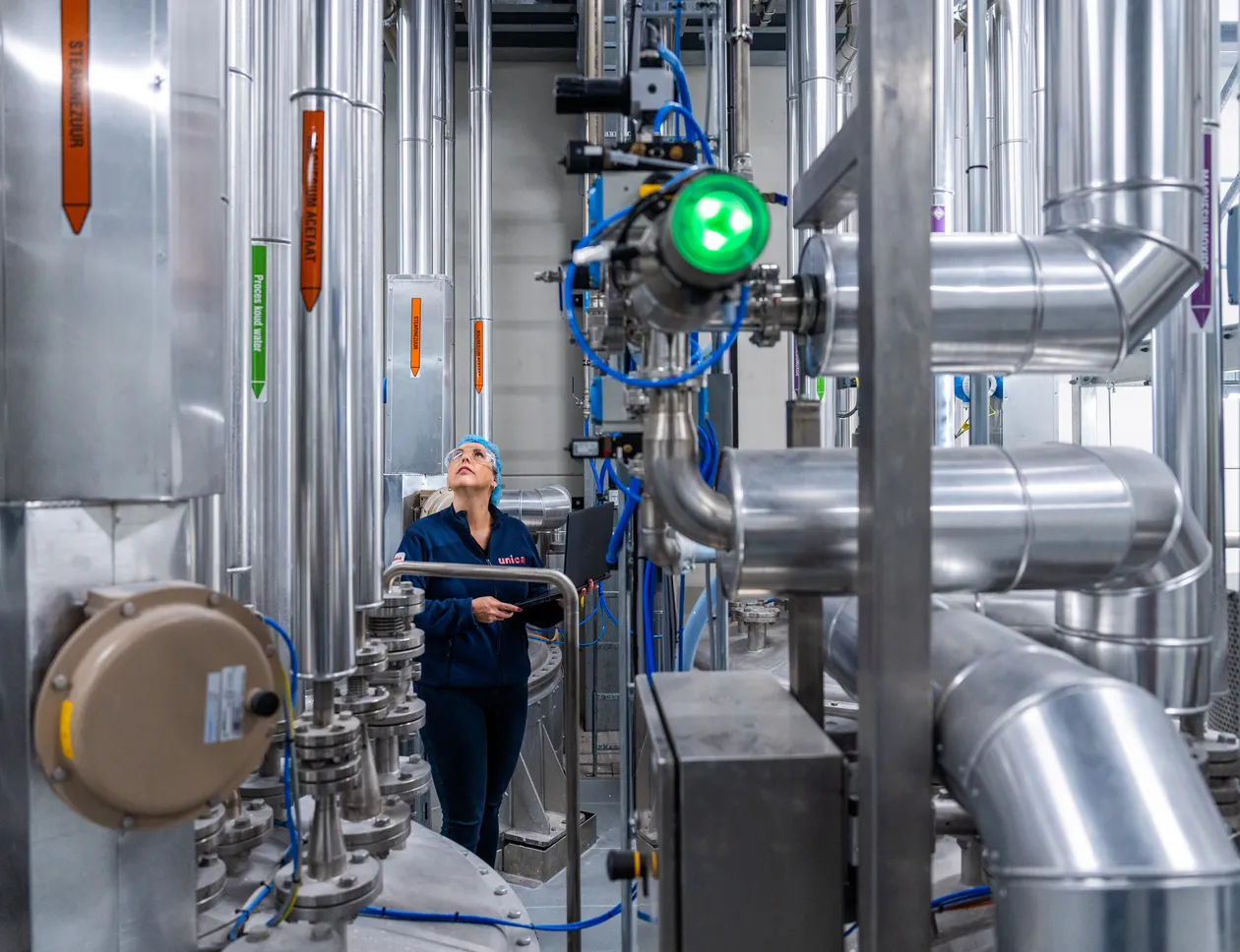 Een medewerker controleert leidingen in een industriële procesomgeving, met nadruk op RVS-installaties en meet- en regeltechniek.