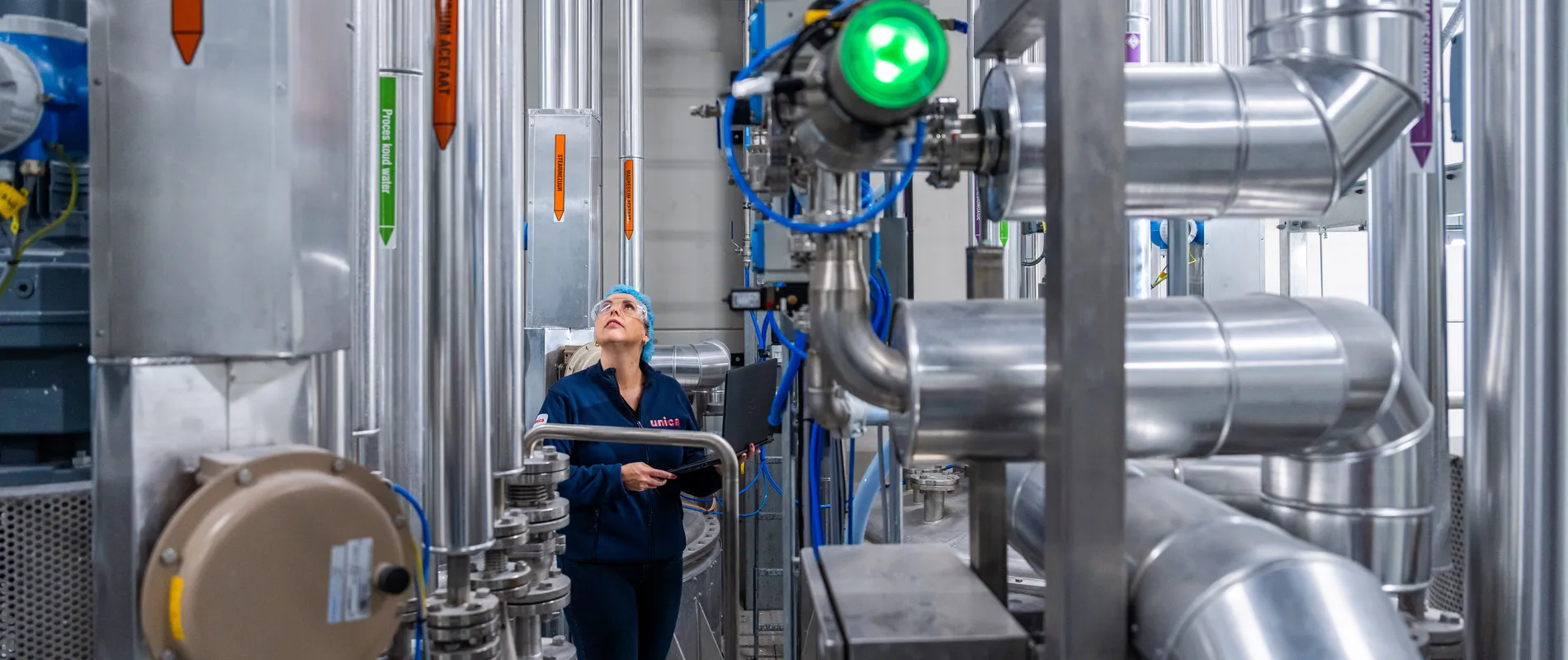 Een medewerker controleert leidingen in een industriële procesomgeving, met nadruk op RVS-installaties en meet- en regeltechniek.