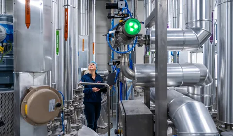 Een medewerker controleert leidingen in een industriële procesomgeving, met nadruk op RVS-installaties en meet- en regeltechniek.