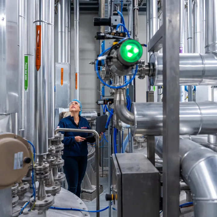 Een medewerker controleert leidingen in een industriële procesomgeving, met nadruk op RVS-installaties en meet- en regeltechniek.