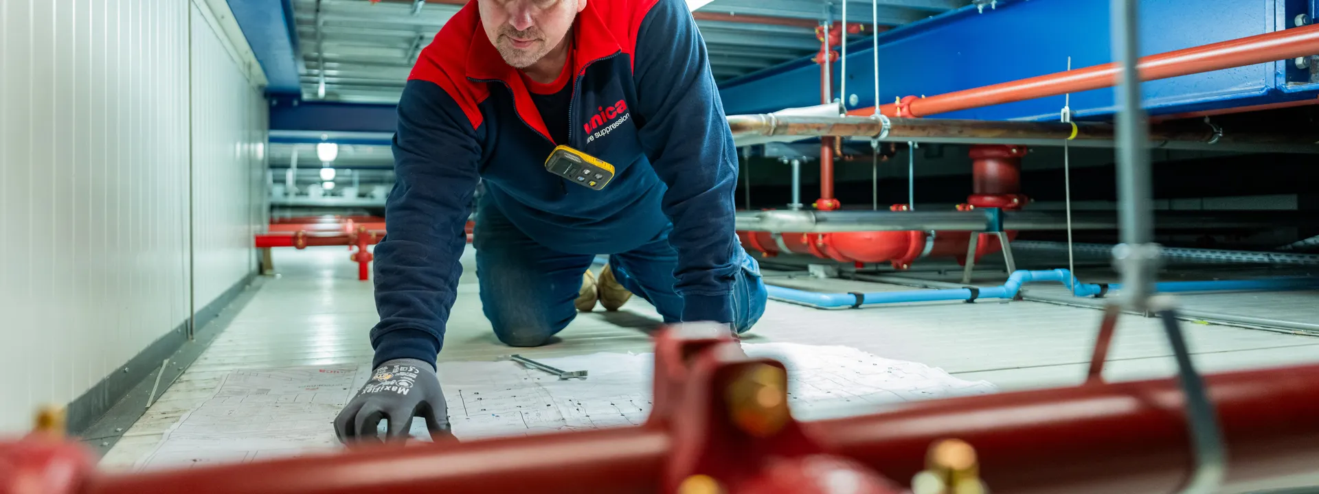 Unica-monteur controleert technische tekeningen tijdens werkzaamheden aan een sprinklerinstallatie.