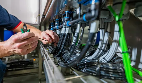 Close-up van handen die industriële kabels bundelen met tie-wraps.