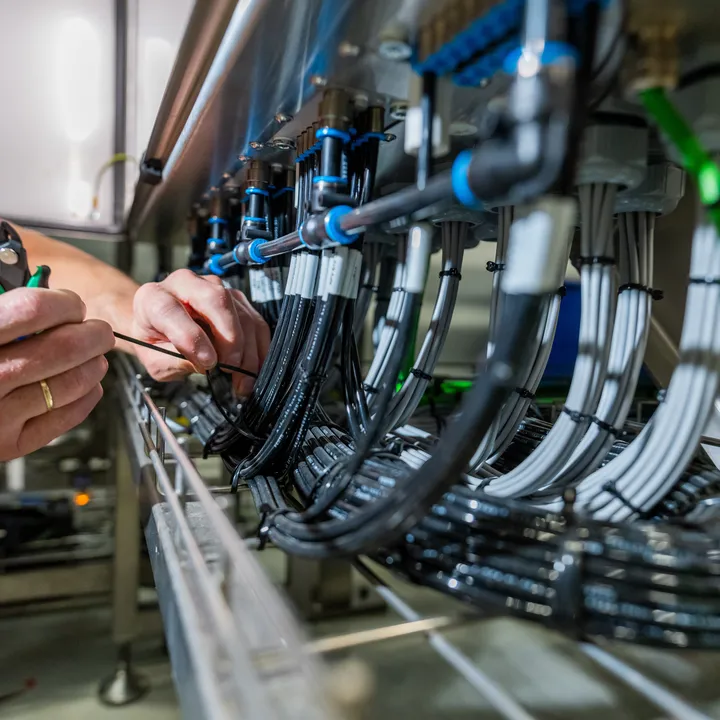 Close-up van handen die industriële kabels bundelen met tie-wraps.