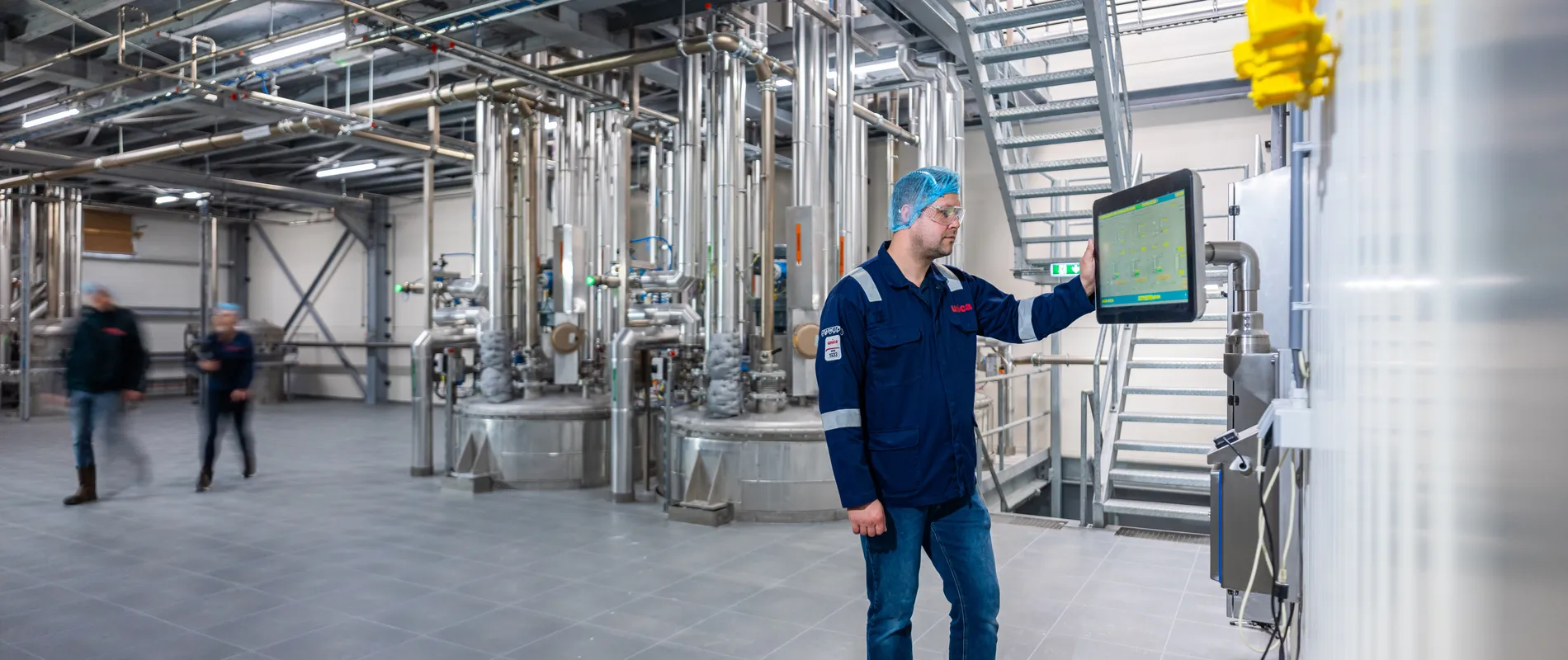 Een Unica-specialist bedient zelfstandig een SCADA-interface in een ruimte met uitgebreide procesleidingen.