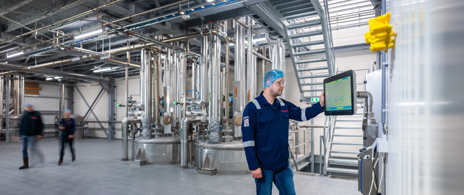 Een Unica-specialist bedient zelfstandig een SCADA-interface in een ruimte met uitgebreide procesleidingen.