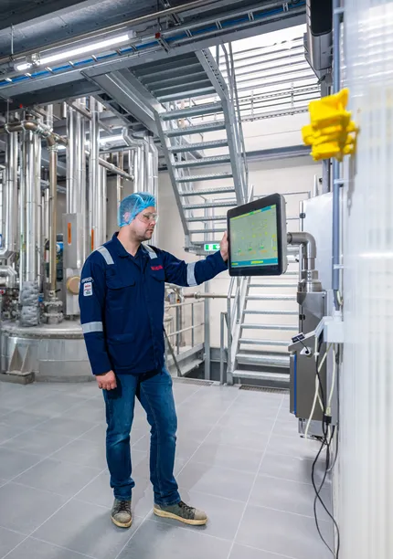 Een Unica-specialist bedient zelfstandig een SCADA-interface in een ruimte met uitgebreide procesleidingen.