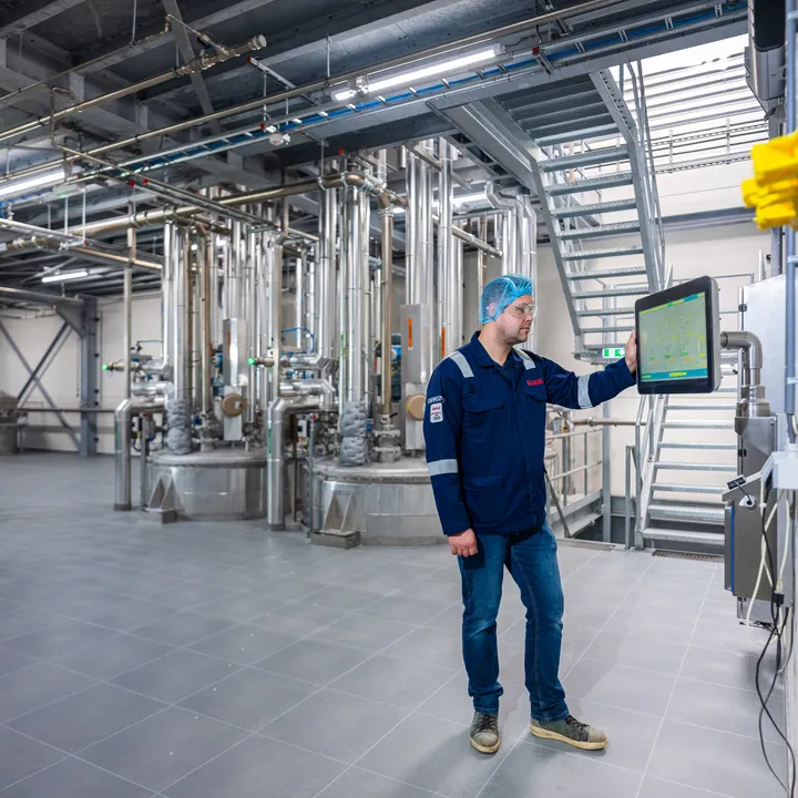 Een Unica-specialist bedient zelfstandig een SCADA-interface in een ruimte met uitgebreide procesleidingen.