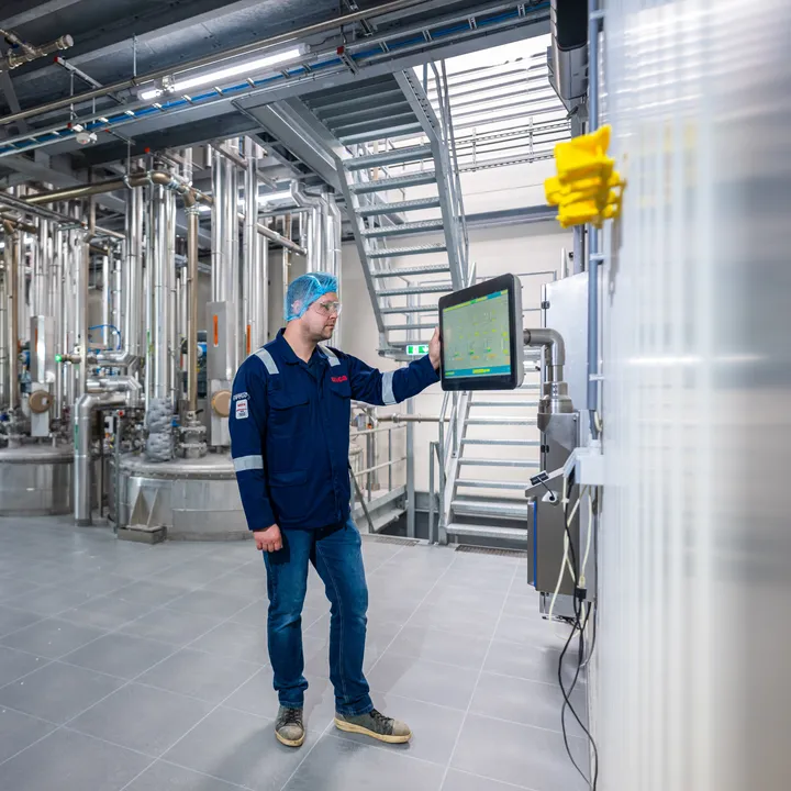 Een Unica-specialist bedient zelfstandig een SCADA-interface in een ruimte met uitgebreide procesleidingen.
