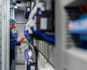 Een Unica-technicus werkt nauwkeurig aan de bedrading van industriële componenten in een krappe schakelkast.