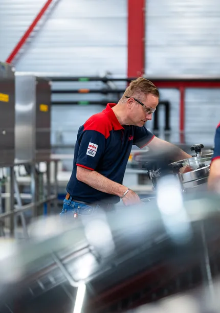 Unica-technicus inspecteert roestvrijstalen tank in een industriële procesruimte