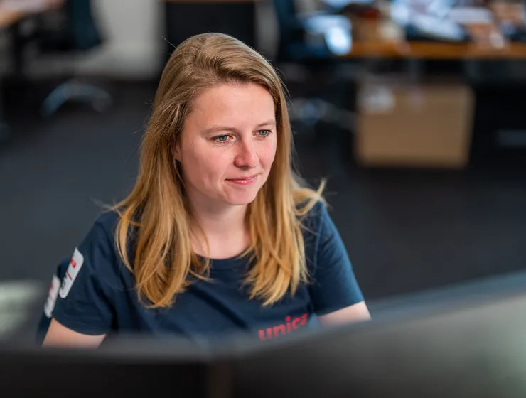 Vrouwelijke medewerker van Unica werkt gefocust achter haar computer op kantoor.