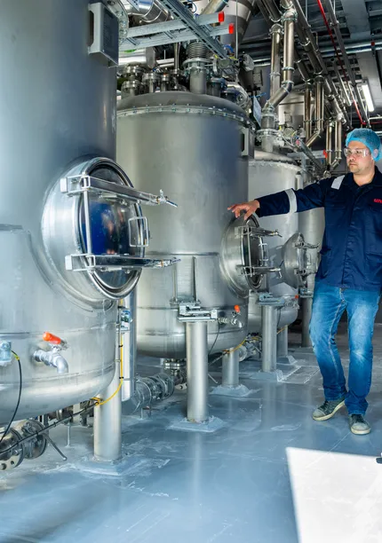 Unica-engineers bespreken een digitaal besturingssysteem via een groot HMI-touchscreen voor procesbewaking.