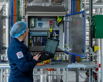 Unica-technica met haarnetje voert configuratie uit aan open schakelkast met laptop