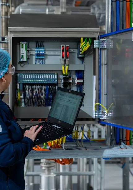 Unica-technica met haarnetje voert configuratie uit aan open schakelkast met laptop