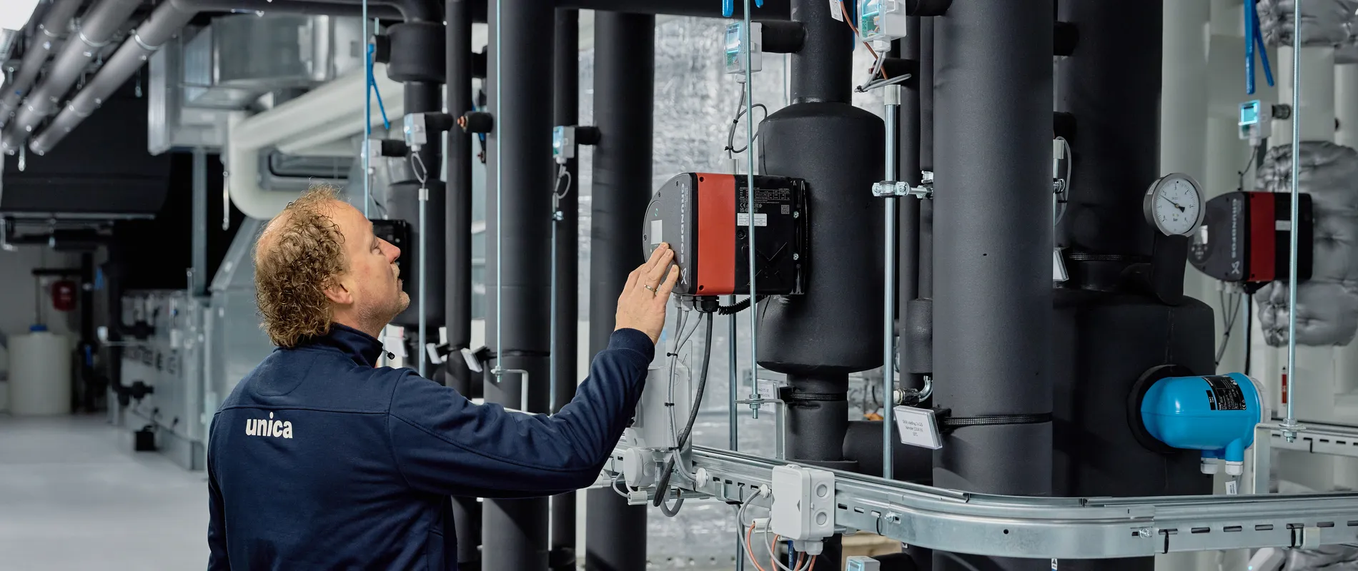 Medewerker van Unica bekijkt de regeltechnische installatie in de technische ruimte