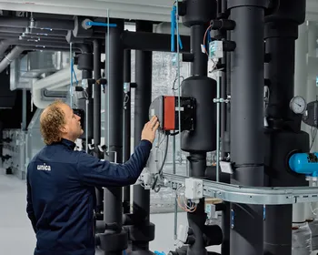 Medewerker van Unica bekijkt de regeltechnische installatie in de technische ruimte