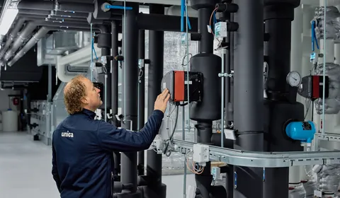 Medewerker van Unica bekijkt de regeltechnische installatie in de technische ruimte