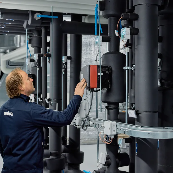 Medewerker van Unica bekijkt de regeltechnische installatie in de technische ruimte