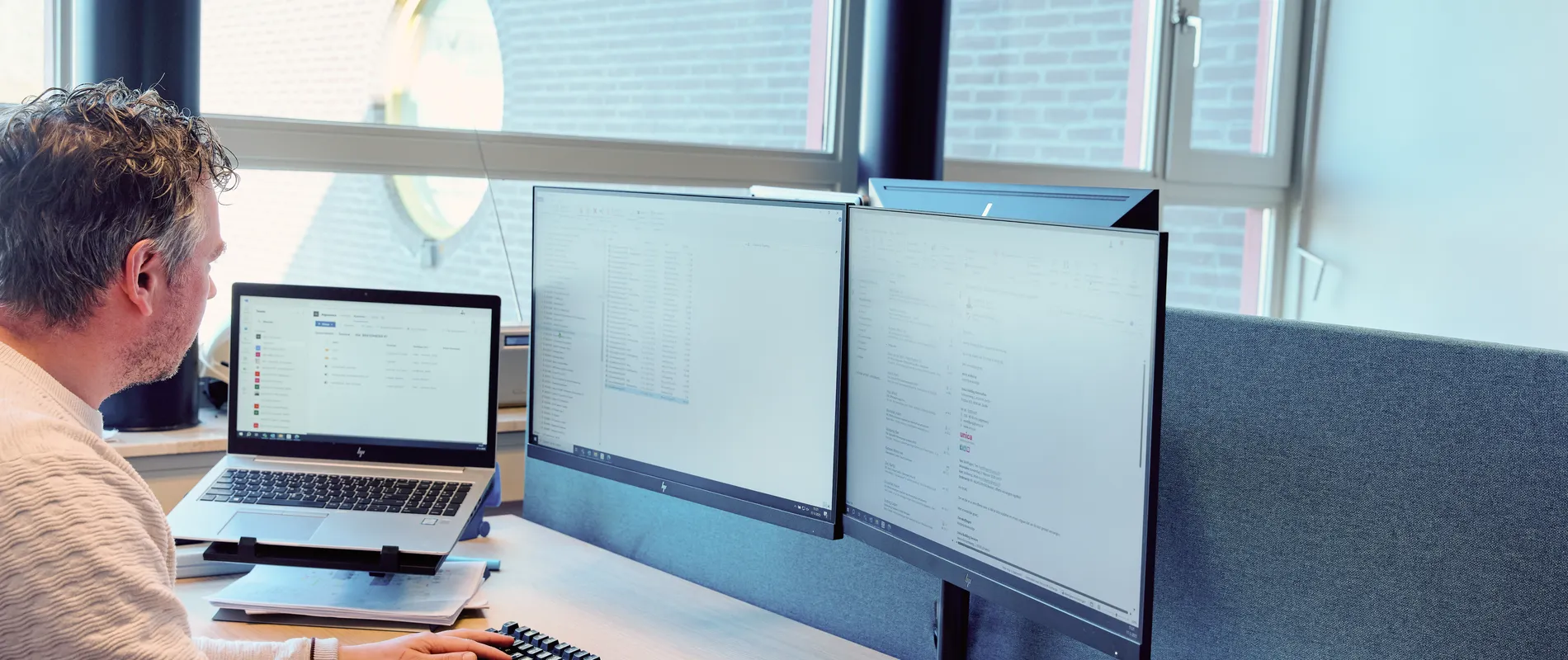 Medewerker van Unica werkt achter de computer met verschillende programma's open