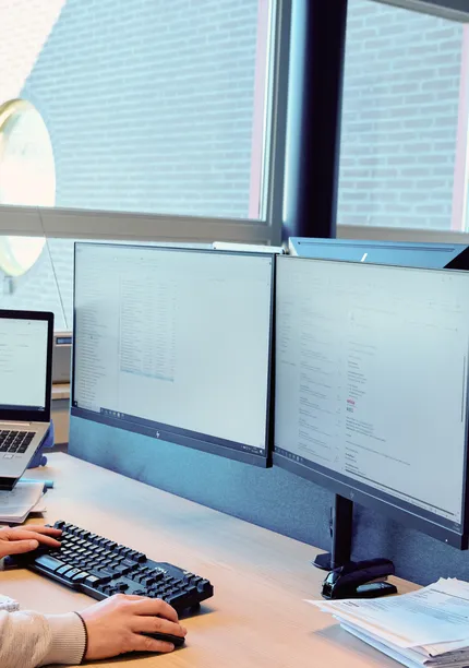 Medewerker van Unica werkt achter de computer met verschillende programma's open